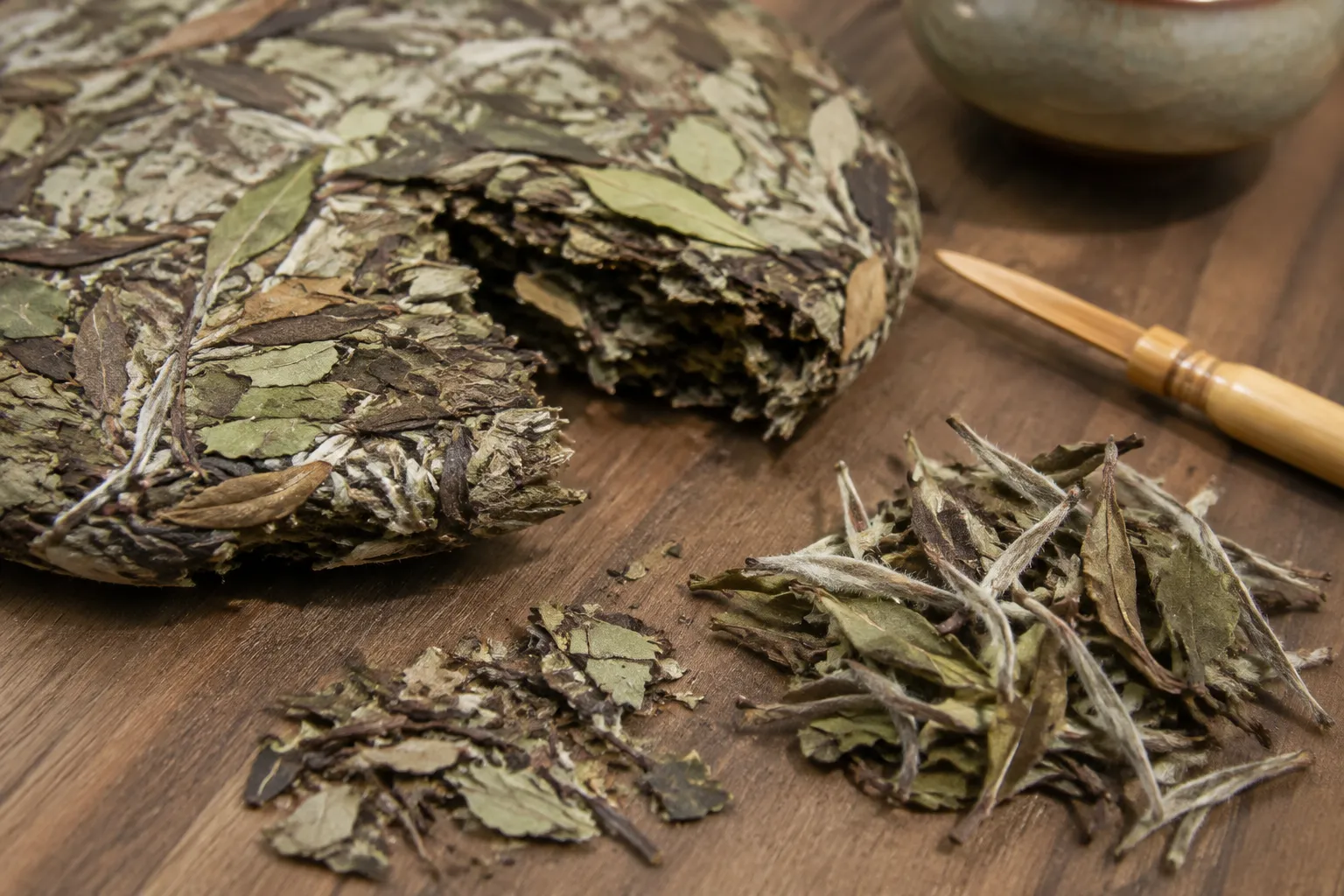 White tea cake fragments and loose leaves arranged for dry-leaf inspection before matched brewing